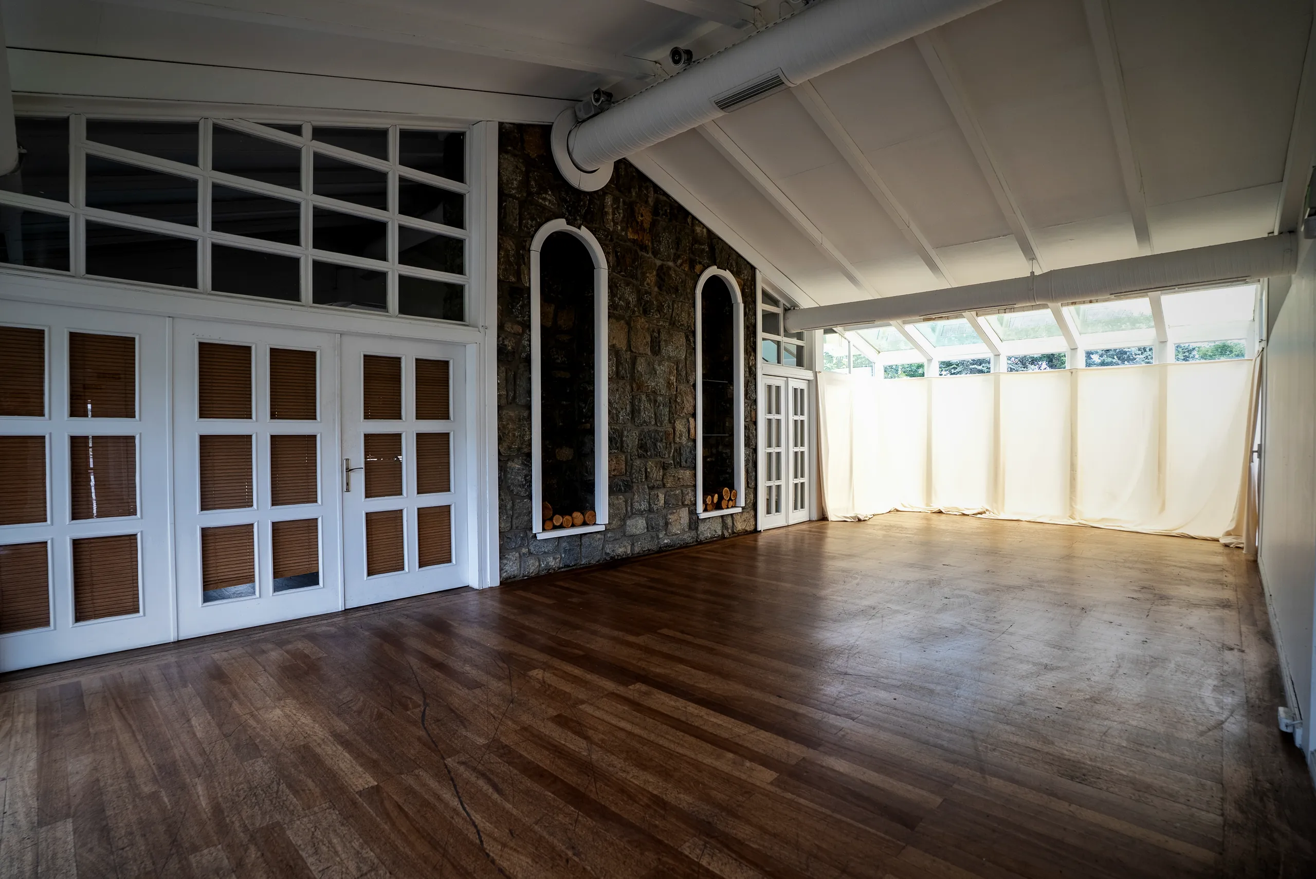 Taş duvarlı, kemer nişli ahşap zeminli salon